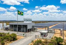 5MW Green Hydrogen Project in Brazil by Linde Subsidiary Hydrogen refueling station with a large HYDROGEN sign, Brazilian flag, and an expansive solar panel field nearby under a blue sky.