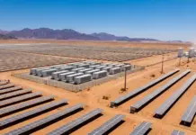$1bn Deal to Build Aqaba Green Ammonia and Hydrogen Plant Extensive desert solar farm with rows of panels, storage units, and distant mountains under a clear blue sky.