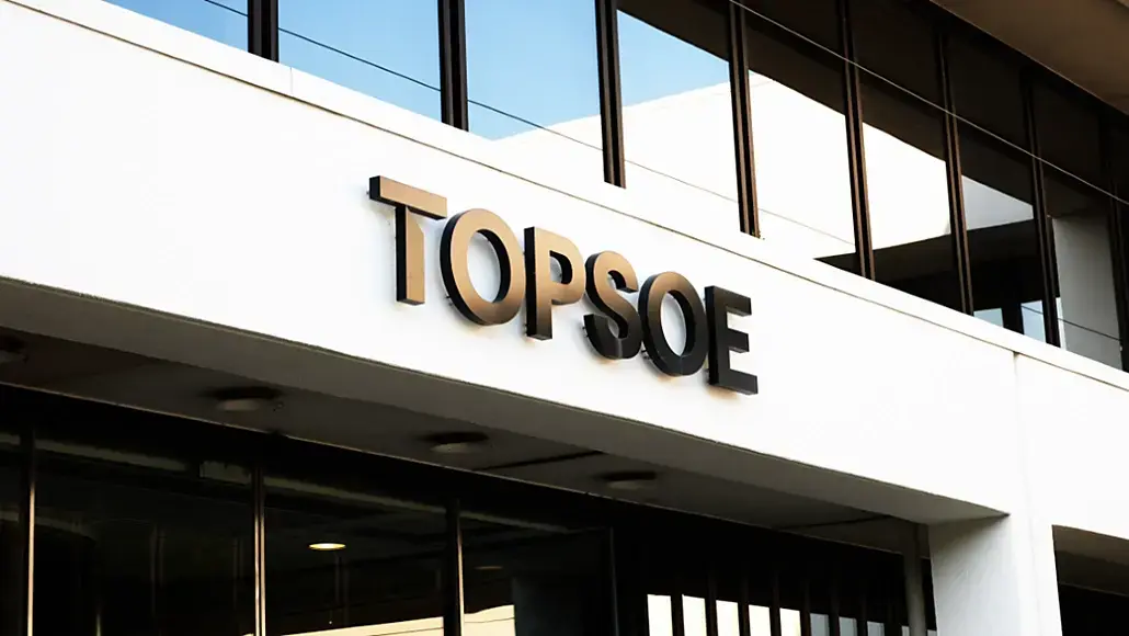 Modern office building facade with a large TOPSOE sign on a white wall and glass windows above