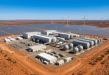 Driving Large-Scale Renewable Hydrogen Projects in Australia Desert solar farm with rows of solar panels and wind turbines in the background; industrial facility with tanks and buildings in the foreground.