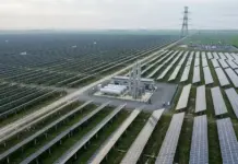 Hydrogen-Storage Project with 50% Green Hydrogen Co-Firing A large solar farm with rows of solar panels, a central equipment yard, and high-voltage transmission towers in a rural area.