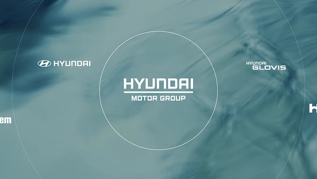 Central Hyundai Motor Group logo inside a white circle on a blue-green abstract background, with Hyundai and Hyundai Glovis logos on the sides.