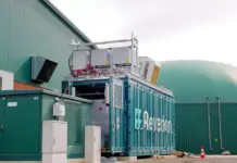 New Hydrogen Fuel-Cell Plant in Germany by HARTING Industrial equipment setup beside a green building; a blue container with branding and exposed electronics on top.