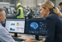 Manufacturers Get More Value from ERP System with Genius ERP Two professionals review data dashboards on dual monitors, including charts and a neural network image, in a modern control room.
